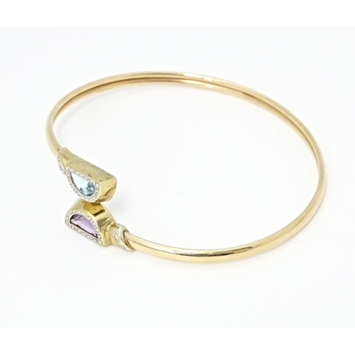 635 - A 9ct gold and yellow metal bracelet of bangle form set with amethyst and topaz.