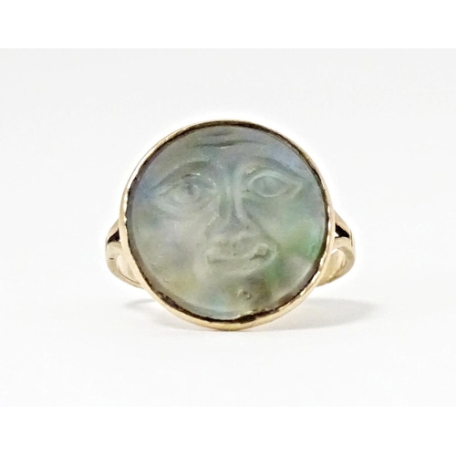 561 - A yellow metal ring set with Man in the Moon cabochon to top. Ring size approx. F 1/2