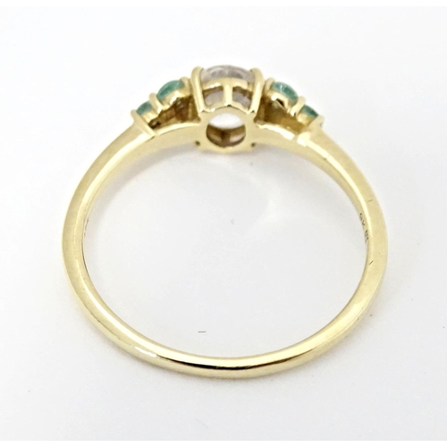 562 - A 9ct gold ring set with central Singida Tanzanian zircon flanked by aquaiba beryl. Ring size approx... 