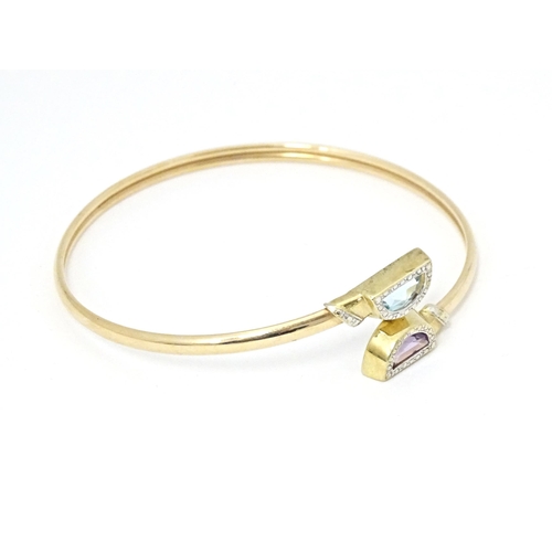 635 - A 9ct gold and yellow metal bracelet of bangle form set with amethyst and topaz.