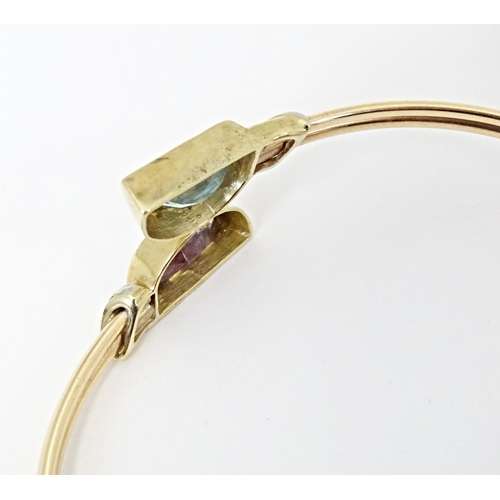 635 - A 9ct gold and yellow metal bracelet of bangle form set with amethyst and topaz.