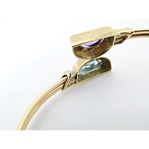 635 - A 9ct gold and yellow metal bracelet of bangle form set with amethyst and topaz.