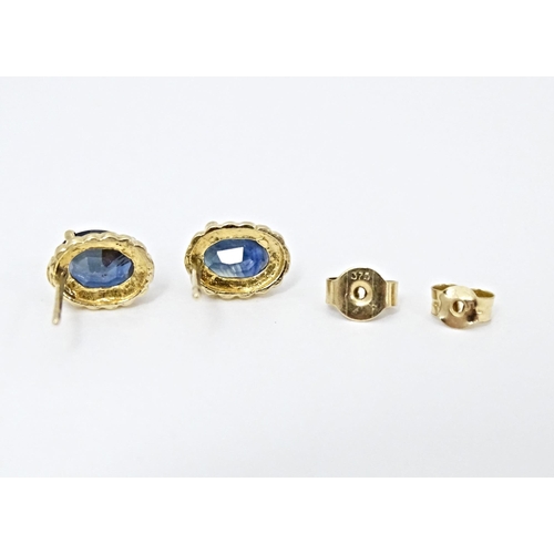 649 - A pair of yellow metal stud earrings set with central sapphire