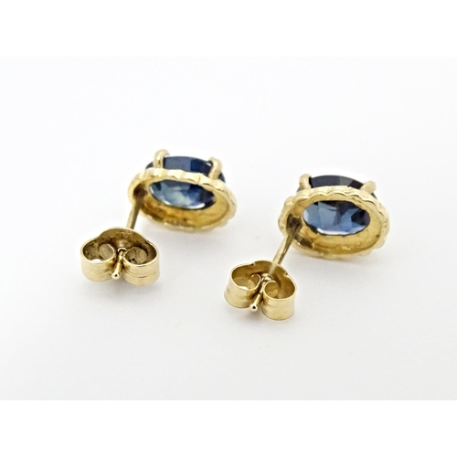 649 - A pair of yellow metal stud earrings set with central sapphire