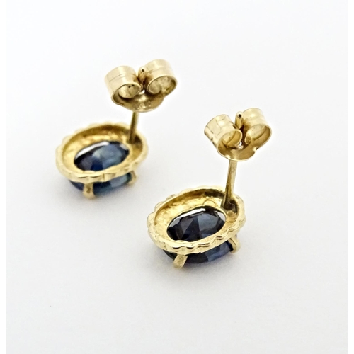 649 - A pair of yellow metal stud earrings set with central sapphire