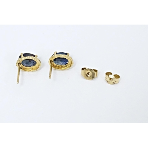 649 - A pair of yellow metal stud earrings set with central sapphire