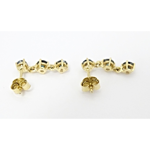 658 - A pair of 9ct gold drop earrings set with blue coloured diamonds. Approx. 1/2