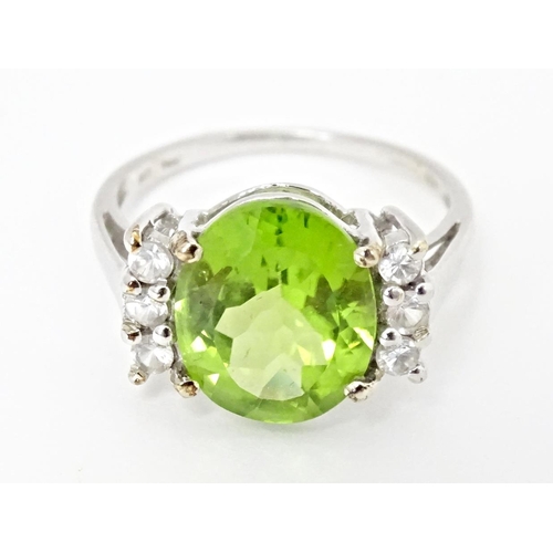 572 - A 9ct white gold ring set with central Changbai peridot flanked by white zircons. Ring size approx. ... 