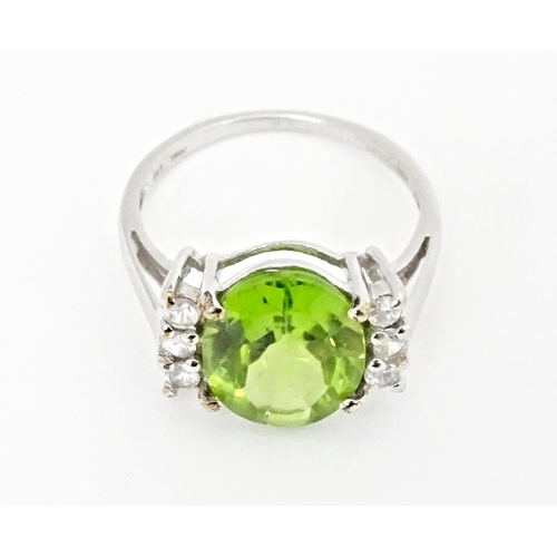 572 - A 9ct white gold ring set with central Changbai peridot flanked by white zircons. Ring size approx. ... 