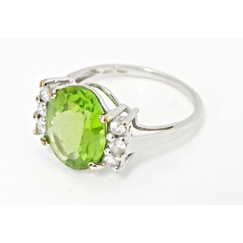 572 - A 9ct white gold ring set with central Changbai peridot flanked by white zircons. Ring size approx. ... 