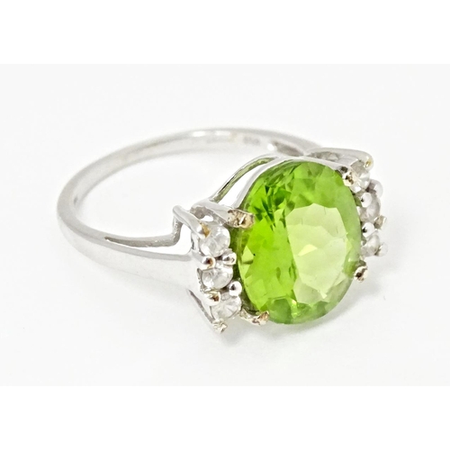 572 - A 9ct white gold ring set with central Changbai peridot flanked by white zircons. Ring size approx. ... 