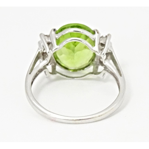 572 - A 9ct white gold ring set with central Changbai peridot flanked by white zircons. Ring size approx. ... 