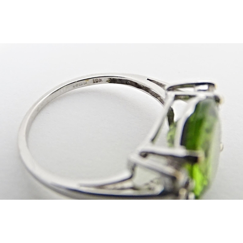 572 - A 9ct white gold ring set with central Changbai peridot flanked by white zircons. Ring size approx. ... 