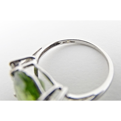 572 - A 9ct white gold ring set with central Changbai peridot flanked by white zircons. Ring size approx. ... 