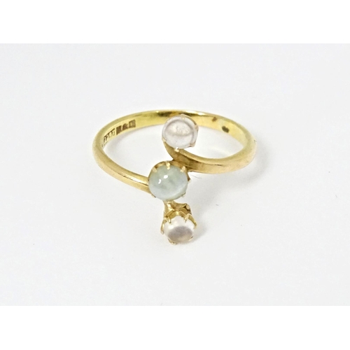 578 - A 22ct gold ring set with central cats eye moonstone and two moonstone cabochons. Ring size approx. ... 