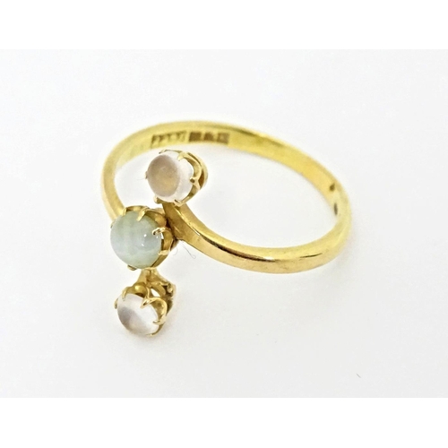 578 - A 22ct gold ring set with central cats eye moonstone and two moonstone cabochons. Ring size approx. ... 