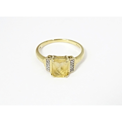 581 - A 9ct gold ring set with central citrine flanked by diamonds. Ring size approx. N