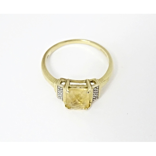 581 - A 9ct gold ring set with central citrine flanked by diamonds. Ring size approx. N