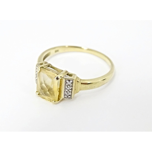 581 - A 9ct gold ring set with central citrine flanked by diamonds. Ring size approx. N