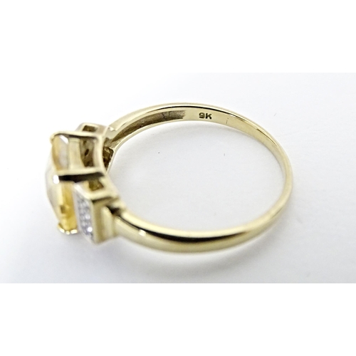 581 - A 9ct gold ring set with central citrine flanked by diamonds. Ring size approx. N