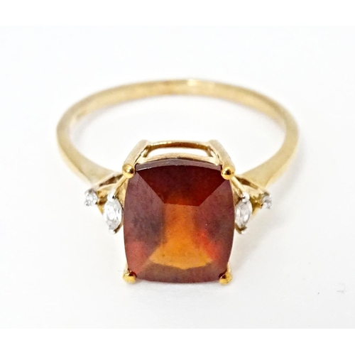 582 - A 9ct gold ring set with gooseberry grossular garnet flanked by white zircons. Ring size approx. R