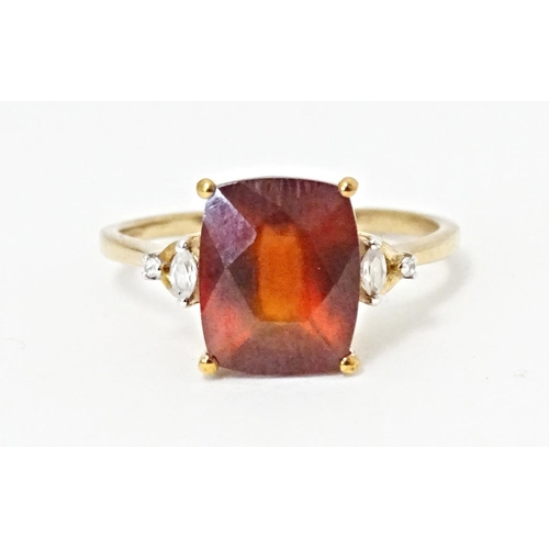 582 - A 9ct gold ring set with gooseberry grossular garnet flanked by white zircons. Ring size approx. R