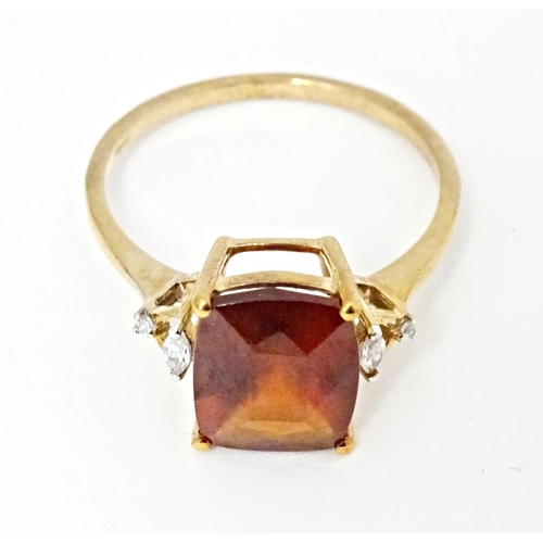 582 - A 9ct gold ring set with gooseberry grossular garnet flanked by white zircons. Ring size approx. R