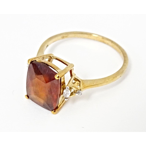 582 - A 9ct gold ring set with gooseberry grossular garnet flanked by white zircons. Ring size approx. R