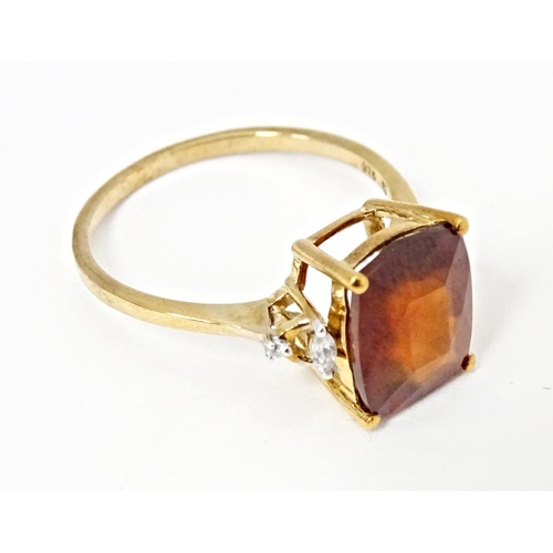 582 - A 9ct gold ring set with gooseberry grossular garnet flanked by white zircons. Ring size approx. R