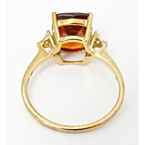 582 - A 9ct gold ring set with gooseberry grossular garnet flanked by white zircons. Ring size approx. R