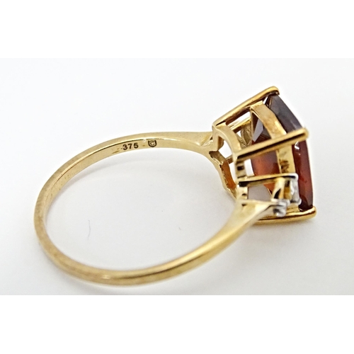 582 - A 9ct gold ring set with gooseberry grossular garnet flanked by white zircons. Ring size approx. R