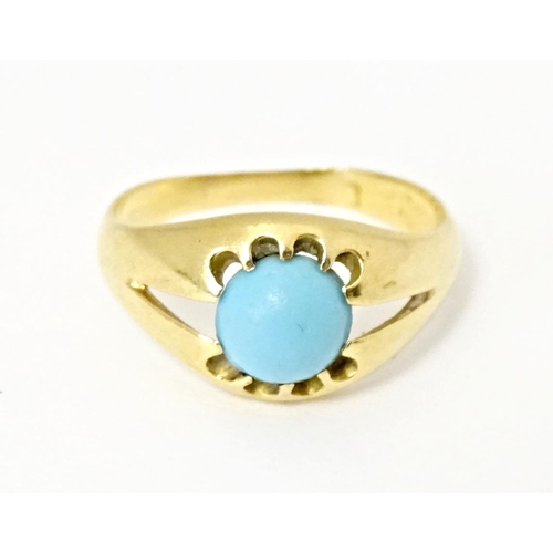 587 - A yellow metal ring set with central turquoise cabochon. Ring size approx. L