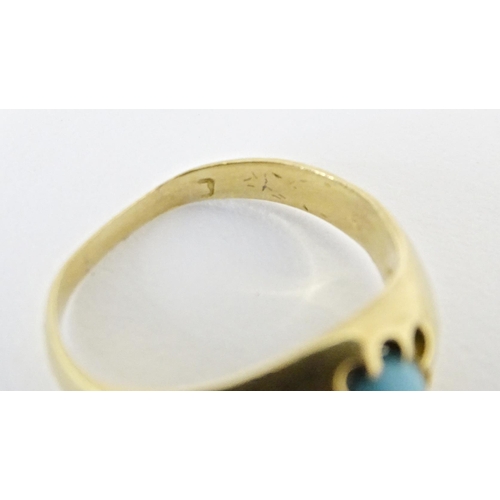 587 - A yellow metal ring set with central turquoise cabochon. Ring size approx. L