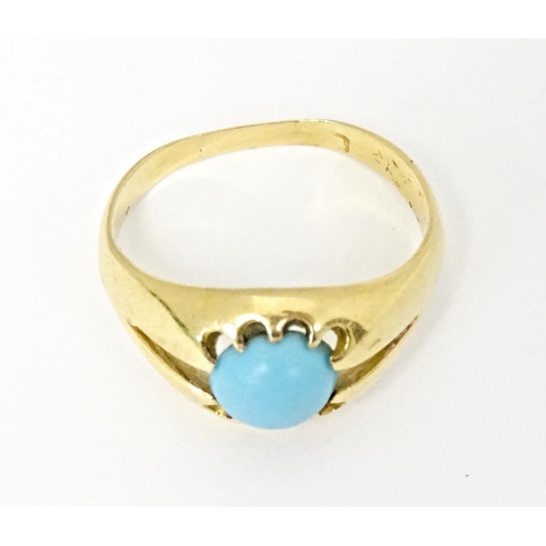 587 - A yellow metal ring set with central turquoise cabochon. Ring size approx. L