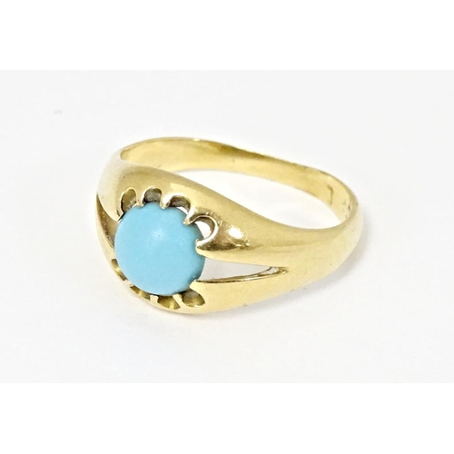 587 - A yellow metal ring set with central turquoise cabochon. Ring size approx. L