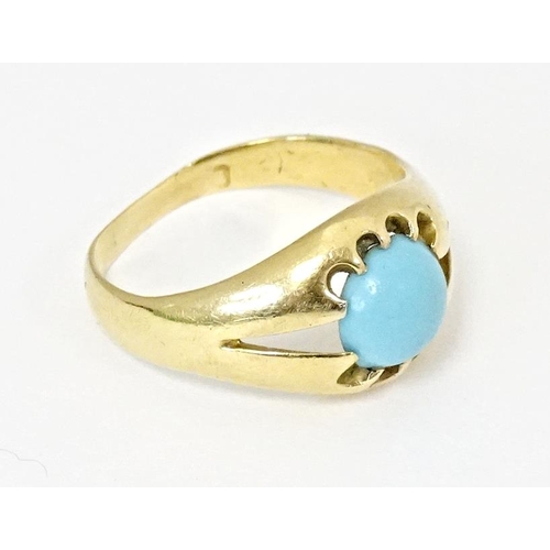 587 - A yellow metal ring set with central turquoise cabochon. Ring size approx. L