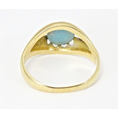 587 - A yellow metal ring set with central turquoise cabochon. Ring size approx. L