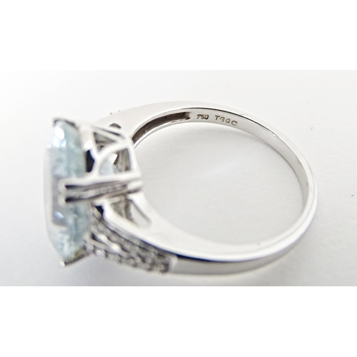 596 - An 18ct white gold ring set with central aquamarine flanked by diamonds. Ring size approx. N