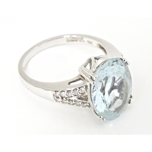 596 - An 18ct white gold ring set with central aquamarine flanked by diamonds. Ring size approx. N