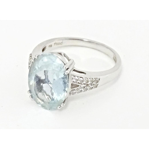 596 - An 18ct white gold ring set with central aquamarine flanked by diamonds. Ring size approx. N