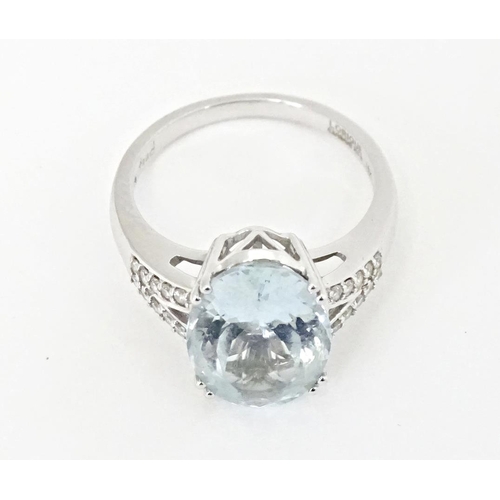 596 - An 18ct white gold ring set with central aquamarine flanked by diamonds. Ring size approx. N