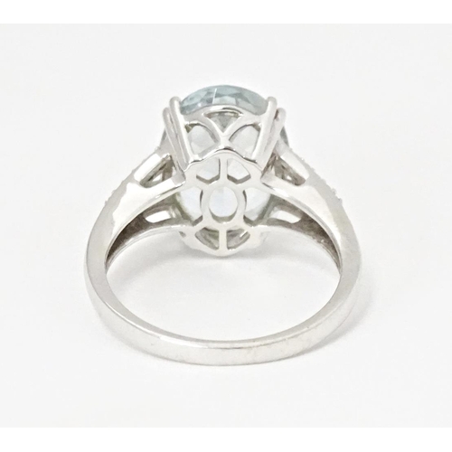 596 - An 18ct white gold ring set with central aquamarine flanked by diamonds. Ring size approx. N