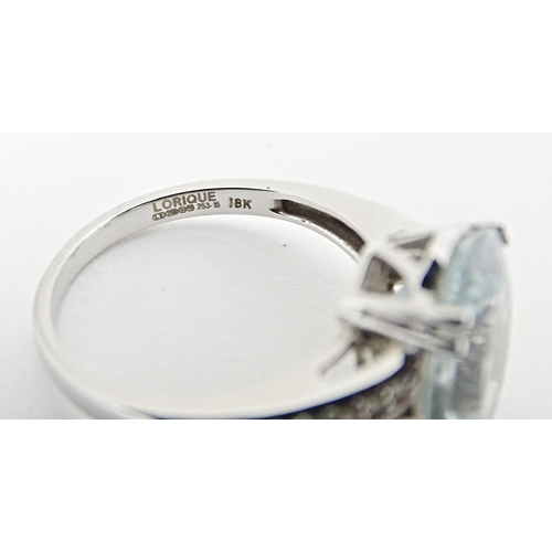 596 - An 18ct white gold ring set with central aquamarine flanked by diamonds. Ring size approx. N