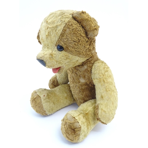 826 - Toy: A 20thC straw filled teddy bear with leather tongue and articulated limbs. Approx. 22 1/2