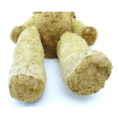 826 - Toy: A 20thC straw filled teddy bear with leather tongue and articulated limbs. Approx. 22 1/2