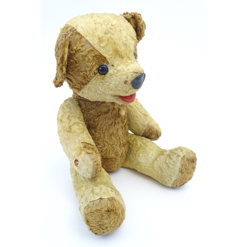 826 - Toy: A 20thC straw filled teddy bear with leather tongue and articulated limbs. Approx. 22 1/2