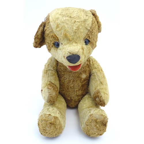 826 - Toy: A 20thC straw filled teddy bear with leather tongue and articulated limbs. Approx. 22 1/2