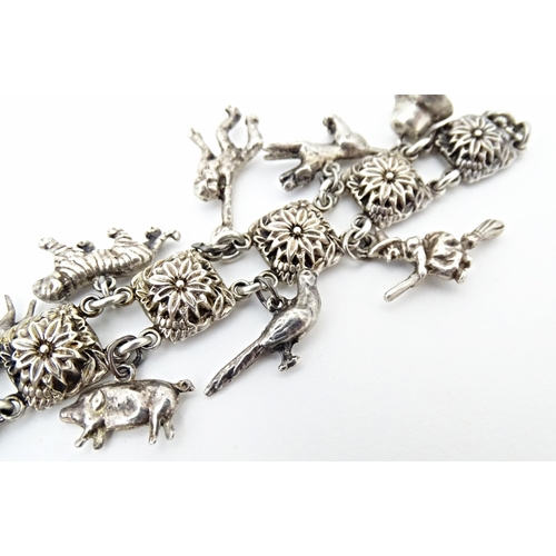 668 - A white metal bracelet set with 13 white metal charms. Approx 7 1/2