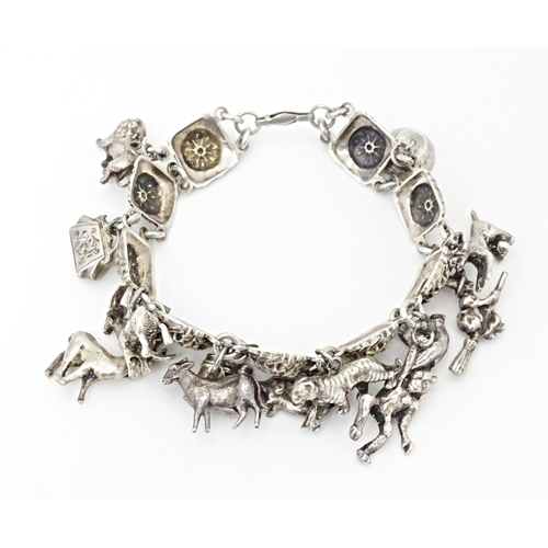 668 - A white metal bracelet set with 13 white metal charms. Approx 7 1/2