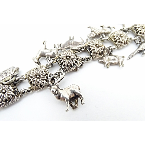 668 - A white metal bracelet set with 13 white metal charms. Approx 7 1/2